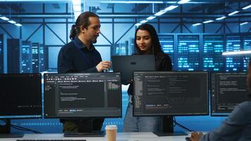 Programmer and supervisor in server room looking for equipment misconfigurations, doing brainstorming. Multiracial colleagues checking data center gear bottlenecks leading to glitches photo