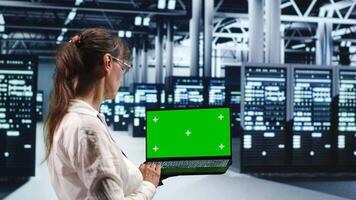 Senior engineer in server room housing high end processors capable of quickly and efficiently performing complex computations and data analysis, using mockup laptop to repair malfunctions photo