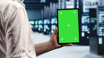 Elderly repairman in data center using mockup tablet to monitor energy efficient servers using renewable sources employed to minimize consumption and reduce overall facility carbon footprint photo