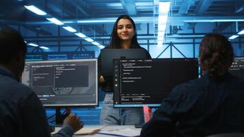 Portrait of smiling Indian manager in server room managing team of engineers looking for equipment misconfigurations. Happy team leader coordinating employees checking data center bottlenecks photo