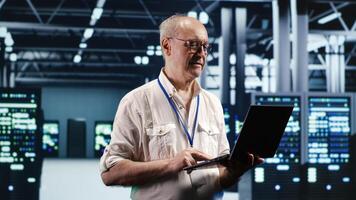 Focused IT professional navigating network of blade servers in industrial hub. Serviceman with laptop ensuring optimum operations, doing optimizations and maintenance in data center photo