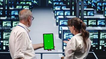 Precise managers looking around high tech data center, using mockup laptop to crosscheck disaster recovery plan and assess servers rigs in need of replacement, preventing complications photo