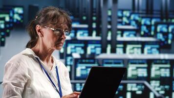 Elderly engineer in data center equipped to handle modern computing requirements, doing regular upgrades to components, increasing processing power, storage capacity and general efficiency photo