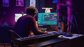 Music engineer using usb stick to edit and add sound effects on audio recording, adjusted volume levels. Artist doing mixing and mastering technique on soundboard, plays piano. Camera B. photo
