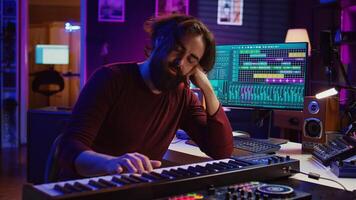 Songwriter getting upset after hearing wrong piano notes, trying to compose a song using midi controller electronic keyboard. Musician playing instrument keys to create the perfect sound. Camera B. photo