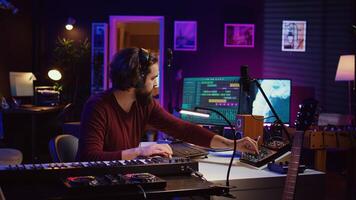 Sound engineer operates recording equipment and oversees audio performances to ensure the perfect notes. Musician composer producing sounds with MIDI controller and mixing console. Camera B. photo