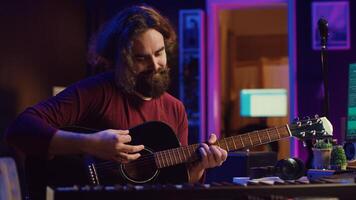 Artist playing guitar and uses DAW software interface to create music, looking at mastering controls on computer screen. Musician recording soundtracks with tools, acoustical engineering. Camera A. photo