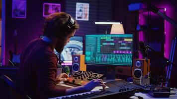 Artist improving the sound quality of audio recordings in home studio, handling mixing console and controls. Producer uses his creative vision to manipulate sounds, audio equipment. Camera B. photo