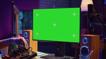 Music producer songwriter mixing piano key notes in home studio, operating with greenscreen monitor on pc. Artist producing sound effects and adjusting volume levels with electronic tools. Camera A. photo