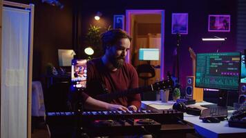 Musical producer doing online guitar lessons with smartphone vlog, recording himself singing and playing acoustics. Artist teaching people how to play and tune instrument with strings. Camera B. photo