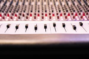 Control panel board desk with sliders and motorized faders in professional recording studio, mixing console used in editing records. Switchers, knobs and buttons used in production. Close up. photo