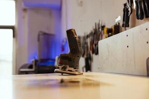 Close up shot of electric router with woodworking tools on rack in background in workshop. Focus on hand powered equipment in front of chisels, screwdrivers, on wall in carpentry studio photo