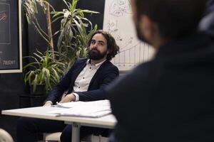 Business analyst listening to a pitch presentation with data reports to evaluate infographics and understand what can be improved, problem solving conference. Specialist identifying issues. photo