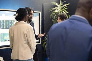 Team of corporate workers preparing their presentation pitch in front of the interactive board, public speakers. Firm colleagues meeting in a conference to review performance indicators as a group. photo