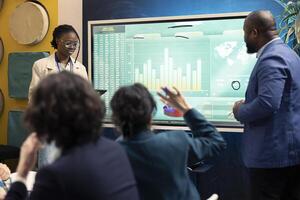 Business team examining worldwide sales process and customer feedback, using interactive board to review funds and profit. Colleagues working on brand differentiation strategies for growth. photo