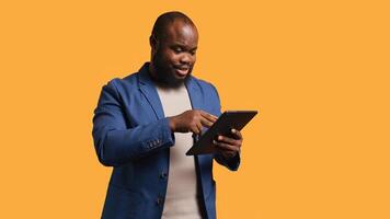 Irked man upset after lacking money while trying to buy stuff online. Grumpy person looking at debit card after getting transaction rejected on tablet, doing facepalm, studio background, camera B photo