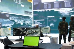 Laptop showing isolated chroma key screen in army monitoring room, military staff working on gathering real time information for a new operation. General headquarters with high tech gear. photo