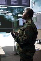 Woman trooper analyzing crucial battlefield data on a big screen in military control center, base of operations. Female engineer collecting and comparing information, reconnaissance. photo