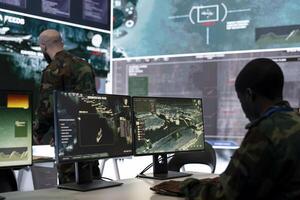 Trooper examines surveillance radar CCTV imagery in control center, monitoring the deployed infantry unit during an ongoing investigation. Army conscript works in reconnaissance division. photo