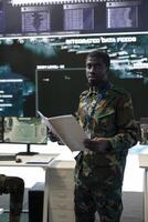 Navy operations specialist reading new mission case files in command center, working with satellite real time data projection on a big screen. Soldier enlisted in national army defense program. photo