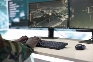 Army IT professional targeting enemy vessels on a gps satellite station world map, operating from command center monitoring room. General studies surveillance CCTV live transmission. Close up. photo