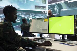 Trooper working on reconnaissance operation with green screen, using military satellite imagery in army control room. Monitoring real time data to help with a national defense mission. photo