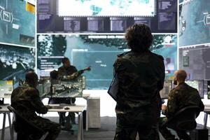 Intelligence analyst supervising and coordinating in the federal data analysis, processing strategic and tactical information to create a new battlefield world map. Military division in control room. photo