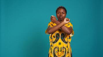 Dissatisfied unhappy person showing a refusal symbol with hands in a stop sign shape, expressing negativity and her rejection for something in studio. Young woman feels displeased. Camera B. photo