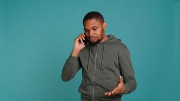 Irked african american man fighting with friends during telephone call, isolated over studio background. Outraged person arguing with mates during conversation on mobile phone, camera B photo