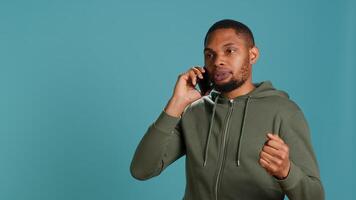 Irked african american man fighting with friends during telephone call, isolated over studio background. Outraged person arguing with mates during conversation on mobile phone, camera A photo