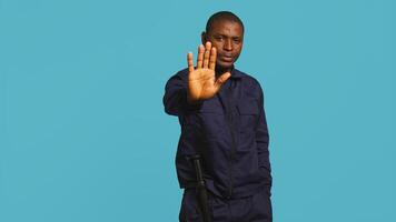 Security guard doing stop sign gesturing, being tasked with preventing criminal activity and detaining suspects. Portrait of stern bodyguard showing halt hand gesture, studio background, camera B photo