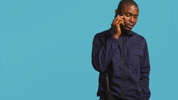 Security guard using cellphone to make call to friends during protection job shift. Portrait of bodyguard in telephone call with mates at work using phone, studio background, camera B photo