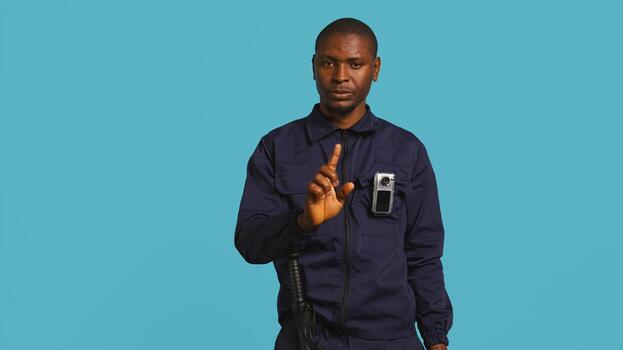 Security guard preventing criminal activity, threatening suspects with active bodycam. Portrait of menacing bodyguard pointing towards security body camera, studio background, camera B photo