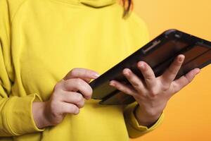 Close-up of female individual using digital tablet while surfing the internet. Caucasian person using a touch screen device while browsing a website on a gadget display. photo