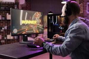 Gamer winning intense singleplayer spaceship arcade racing videogame on powerful gaming computer system with neon lights. Man feeling relaxed after finally passing difficult game level photo