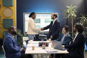 Company principal does handshake with a new woman employee during an introductory meeting, welcoming her to the team and introducing her to other colleagues. Manager shaking hands with trainee. photo