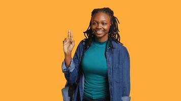Smiling african american student at school raising arm to answer question, isolated over studio background. Cheerful girl with hand up volunteering to tell teacher explanation to question, camera A photo