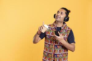 Man having boost of serotonin while sipping tasty coffee and texting friends using phone, listening music. Thrilled person enjoying leisure time, tasting hot beverage, chatting with mates photo