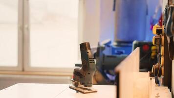 Close up of electric router on spindle moulder in furniture assembly shop with woodworking tools on rack in background. Focus on hand powered equipment used for sanding wood in studio, panning shot photo