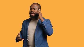 Irked african american man fighting with friends during telephone call, isolated over studio background. Outraged person arguing with mates during conversation on mobile phone, camera A photo