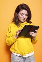 Close-up of caucasian woman utilizing tablet with a touch screen. Smiling female individual holding digital device and looking at screen, working on online related projects. photo