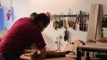 Woodworker using bench vise to hold lumber block, starting furniture assembling in workshop. Craftsperson in joinery using vice tool to clamp piece of wood before carving it, camera A photo