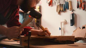 Artisan using bench vise to hold timber block, carving intricate designs into wood using chisel and hammer. Artist uses vice tool to clamp piece of wood, shaping log with tools, camera B close up shot photo