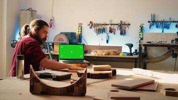 Upbeat men using CAD software on isolated screen laptop, debating wood design to use. Smiling cabinetmakers chatting, using program on chroma key notebook to make furniture schematics, camera B photo