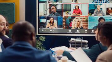 Business associates meeting with stakeholders on a videocall connection, sharing insight and updates on a new development project. Executive board members discussing about firm growth. Camera A. photo