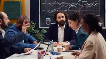 Business analysts meeting in a boardroom to discuss project stages and updates, gathering information from data reports and planning steps to coordinate with objectives. Employee engagement. Camera A. photo