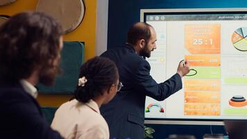 Sales manager creates a presentation to pitch in a new strategy for development, using interactive board to make his staff members understand the objectives. Business planning meeting. Camera A. photo