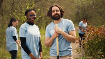 Portrait of diverse activists team tidying natural environment by working on reforestation and engaging in litter cleanup, recycle garbage. Volunteers protecting wildlife and ecosystems. Camera A. photo