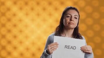 Woman holding message in hands urging people to read more, talking about importance of lecture, isolated over studio background. Bookworm promoting literacy concept, camera A photo