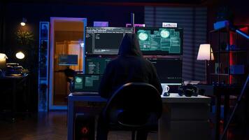 Hacker arriving in secret base with laptop, ready to start programming viruses. Scammer in criminal den opening notebook to exploit network servers and bypass security measures, camera B photo